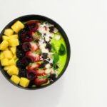 Delicious mixed fruit bowl with mango, blackberry, and cherry atop a creamy base. Perfect for a healthy diet.