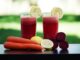 Colorful glasses of beetroot and carrot juice garnished with lemon slices, symbolizing health and freshness.