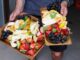 a person holding two trays of fruit